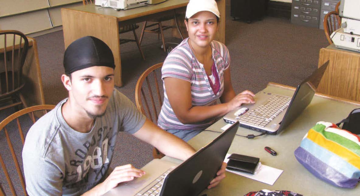 Two people with laptops sitting at a table.